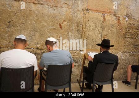 Jews praying during sabbath inside Western Wall. Western Wall in the Old City of Jerusalem, a place of prayer and pilgrimage sacred to the Jewish people. It is the only remains of the Second Temple of Jerusalem, held to be uniquely holy by the ancient Jews and destroyed by the Romans in 70 AD. The authenticity of the Western Wall has been confirmed by tradion, history, and archaeological research; the wall dates from about the 2nd century BC Stock Photo