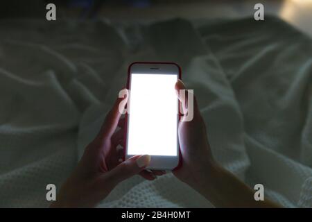 Mobile addiction, insomnia, sleep disorder concept. Sleepless woman chatting and surfing on internet with smartphone at late night, lying on bed under Stock Photo