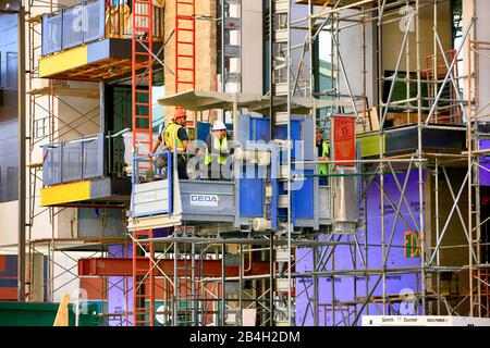 Building site elevator with men descending and ascending wearing safety apparel in Tucson AZ Stock Photo