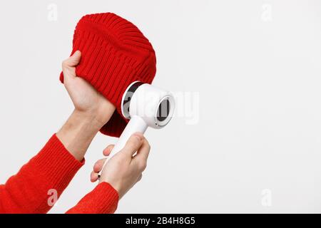 Man holding in his hands a device for removing lint from acrylic or wool on a beanie. Electric device after cleaning and collected fluff/lint, isolate Stock Photo