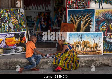 Destination Tanzania, Zanzibar Island: Impressions from Stone Town. Two children playing a board game in front of an art shop. Stock Photo