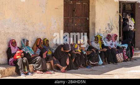 Destination Tanzania, Island Zanzibar: Impressions from Stone Town, the oldest district of Zanzibar City, the capital of the Tanzanian state Zanzibar at the end of Ramadan. Women wait in the shade until they can go shopping for the sugar festival. Stock Photo