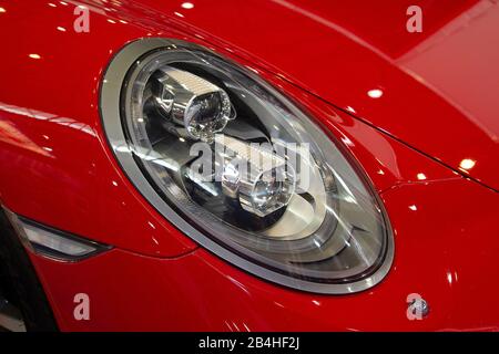 Close up shot of headlight in luxury red car background. Stock Photo