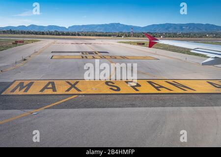 View from the window of an airplane on the runway of Palma de Mallorca with mountain range and airfield markings Stock Photo