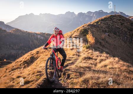 A man rides an ebike MTB on the tracks in the San Nicolò valley, Fassa valley, Trentino, Dolomites, Italy