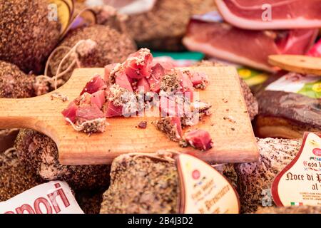 Europa, Italien, Piemont, Cannobio. Auf dem Wochenmarkt bietet ein Händler seine Wurst in kleinen Stücken zum Probieren an. Stock Photo