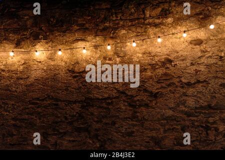 Europe, Italy, Piedmont, Cannero Riviera. A string of lights illuminates a house wall in the old town in the evening. Stock Photo