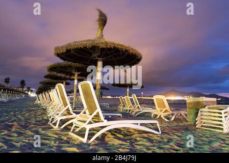 Spain, Mallorca, Playa de Muro, umbrellas and sun loungers on the beach Playa de Muro at the blue hour, north of Majorca. Stock Photo