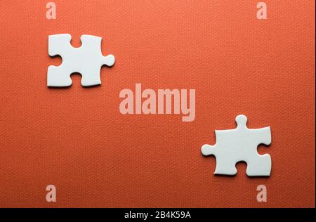 two separate white puzzle pieces on an orange background Stock Photo