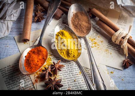 Spoon with spices, anise and cinnamon on old book pages Stock Photo