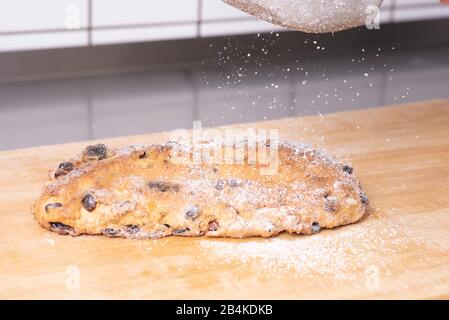 Powdered sugar falls on a freshly baked Christmas stollen. Stock Photo