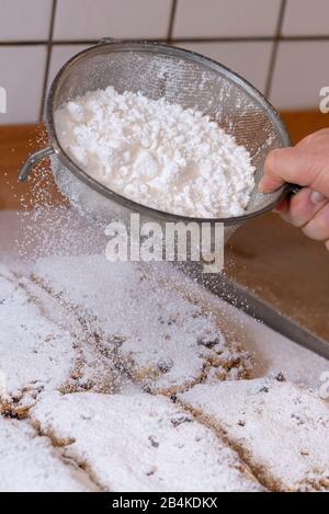 Baker strews powdered sugar on Christmas stollen. Stock Photo