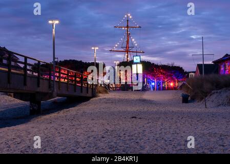 Germany, Medcklenburg-Vorpommern, Zingst, view from the beach onto the winter market, illuminated ship mast, clock. Stock Photo
