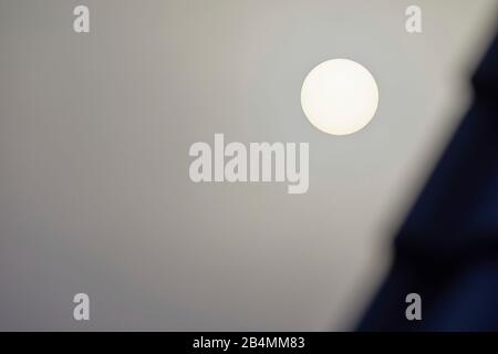 The sun behind thick clouds in the dark gray sky Stock Photo