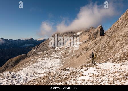 Mountaineer with a large backpack and sticks in the high mountains of the Karwendel Stock Photo