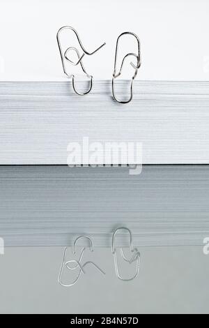 Paper clips are having a conversation, reflection Stock Photo