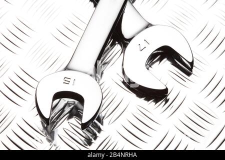 Two new chrome silver open end wrenches on a diamond plate metalic background Stock Photo