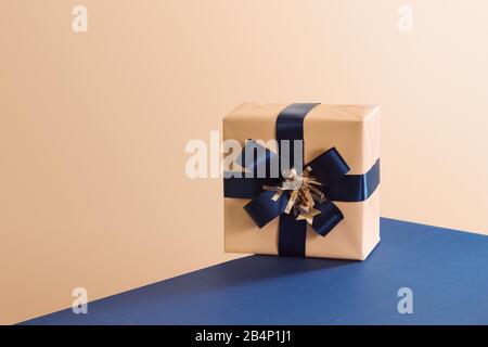Wrapped gift box with blue ribbon bow, isolated on blue background Stock Photo