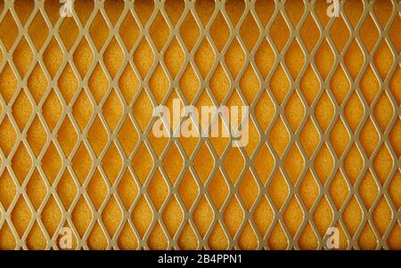 Texture of metal mesh and yellow foam lining. In foam rubber, pores are clearly visible. Stock Photo