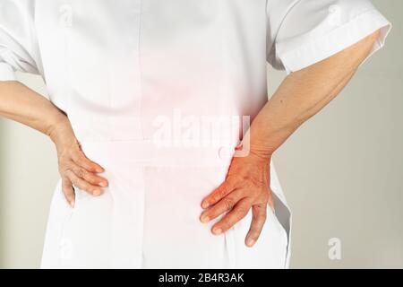 senior doctor woman suffering of backache, touching back with hand, muscular pain over white background Stock Photo