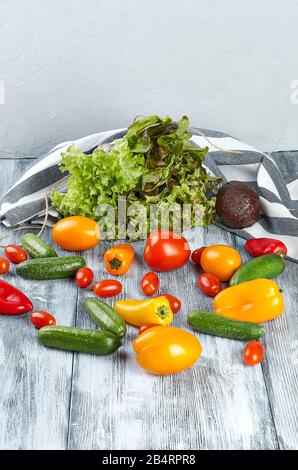 Fresh mini vegetables, tomatoes, cucumbers, paprika, avocado and greens on a gray background. Stock Photo