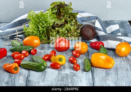Fresh mini vegetables, tomatoes, cucumbers, paprika, avocado and greens on a gray background. Stock Photo