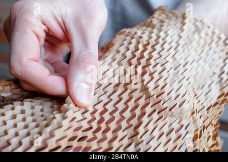 Examine the packaging. Touch the thin brown paper into the grid. New type of packaging. Stock Photo