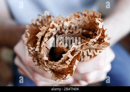 Brown paper in the hands. Thin packaging folded in several layers. Stock Photo