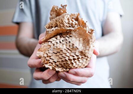 Round ball of brown paper in the hands. Thin mesh of brown paper. Side view. Stock Photo