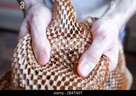 Examine the packaging. Touch the thin brown paper into the grid. New type of packaging. Easy to tear. Stock Photo