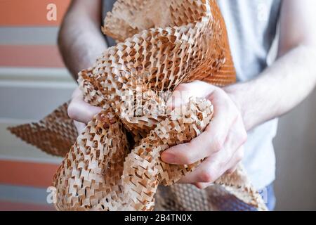 A man wrinkles paper. Thin mesh of brown paper. A new type of packaging. Stock Photo