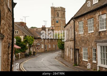 Looking down Market Street with its old stone houses towards St Nicholas church in Abbotsbury in Dorset, England. Stock Photo