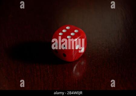 A red die on a wooden table showing a result of six Stock Photo