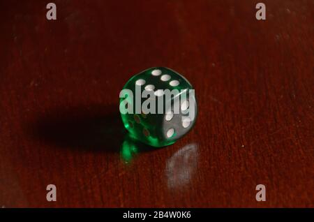 A green die on a wooden table showing a result of six Stock Photo
