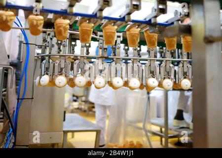 Close-up shot of moving conveyer with ice-cream cones ready for packing. Frozen desserts production at the factory. Stock Photo