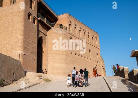 Iraq, Iraqi Kurdistan, Arbil, Erbil. A family is walking up the road to the entrance of the Qalat citadel in Erbil. A bird is flying by on the right Stock Photo