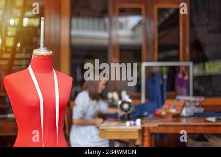 Red dummy with measuring tape in tailors studio. sewing workshop, Stock Photo