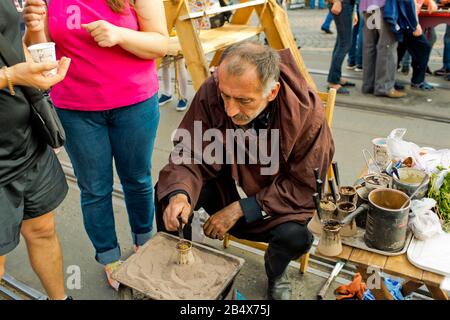 Vinnytsia Ukraine - September 09, 2017: Birthday of the city of Vinnytsia. A man in a brown hoodie is brewing coffee on the sand. Stock Photo