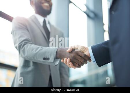 Horizontal close up shot of two unrecognizable businessmen standing in front of each doing handshake Stock Photo