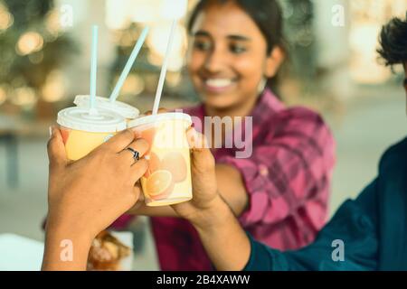 Selective focus on friends hands cheers Juice paper cups - Group of best Friends enjoying time or having fun at cafe, Best friendship concept - Young Stock Photo