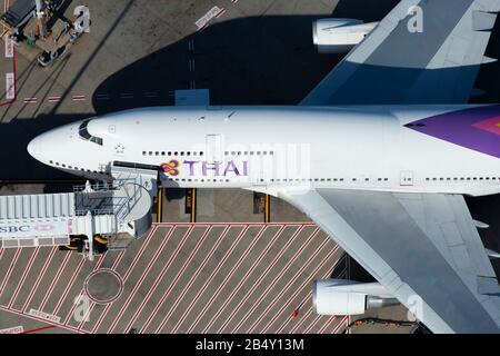 Thai Airways International Boeing 747 parked at a gate with jet bridge for passengers to board in an airport terminal. Boeing 747-400 HS-TGY. Stock Photo