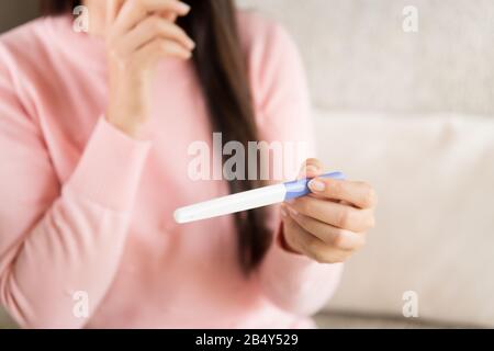 Woman with pregnancy test positive result, focus on foreground 2 stripes. Stock Photo