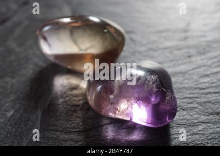 Ametrine tumbled pebbles on gray slate background Stock Photo