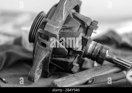 Car generator rotor on a workbench closeup. Disassembled Used Automotive DC Generator. Auto repair shop or service center. Selective focus. Side view. Stock Photo