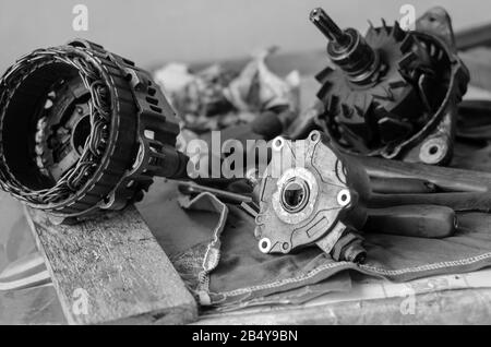 Details of a car generator on a workbench. Disassembled Used Automotive DC Generator. Repair used generator. Auto repair shop or service center. Selec Stock Photo