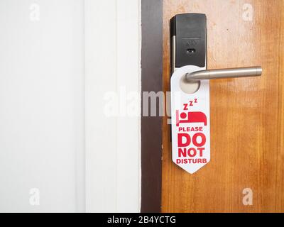 Do not disturb sign attached to the front of the room that is closed inside the hotel on the wooden door with stainless steel handles and use the elec Stock Photo