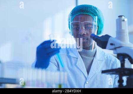 Horizontal chest up portrait of young male medical scientist wearing protective mask doing laboratory tests, copy space Stock Photo