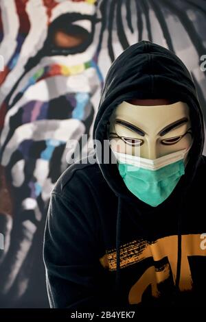 Rastatt/ Germany - March 07 2020: Anonymous hacktivist wearing a medical mask against coronavirus and other diseases and epidemics. Activist hacker Stock Photo