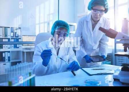 Horizontal portrait of two young scientists wearing protective uniform coworking in modern medical laboratory, copy space Stock Photo
