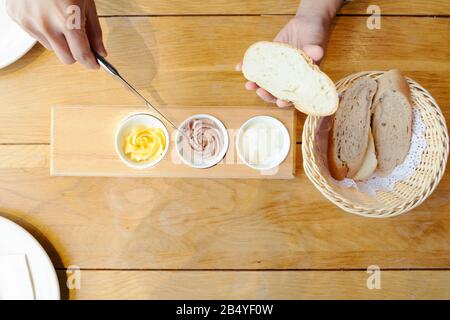 Woman hand spreading butter on sliced bread Stock Photo
